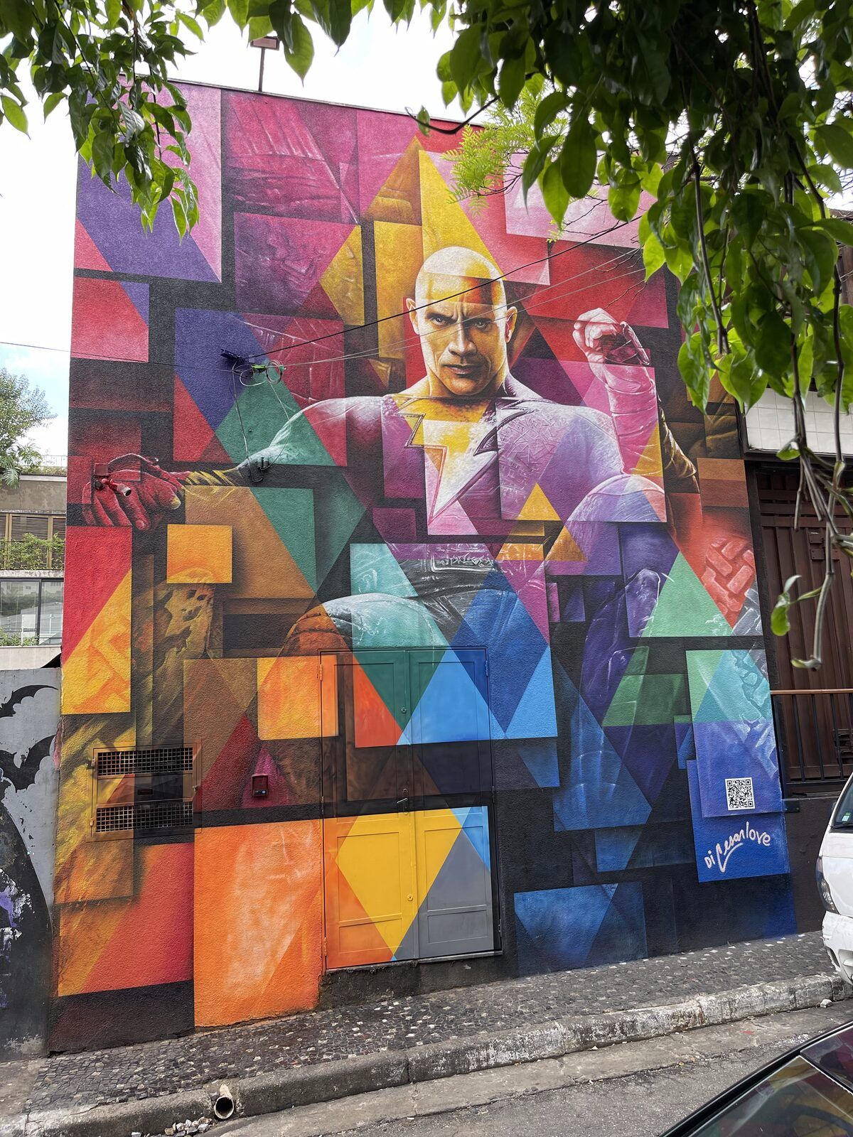 Mural de fachada: figura masculina em terno, construída em blocos geométricos coloridos.